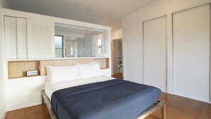 A bedroom with a bed, a bedside table, a wardrobe, and a mirror.