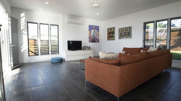 Ein modernes Wohnzimmer mit einer Couch, einem Fernseher und Kunstwerken an der Wand.