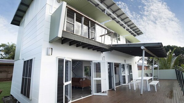 A two-story house with a deck, sliding glass doors, and a covered patio area.