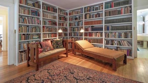 Een bibliotheek met boekenkasten, een bank, een zitbank en een kamerbreed tapijt.