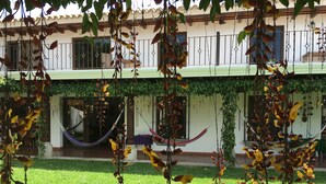Un edificio con un balcone, un'amaca e piante pensili.