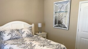 Ein Schlafzimmer mit einem Bett, einem Nachttisch, einer Lampe und einem gerahmten Kunstwerk an der Wand.
