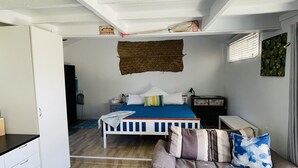 A bedroom with a bed, a sofa, a desk, and a window with blinds. - Great Value steps from Muri Beach with Kayaks, Paddle Boards, Pool, Free WIFI ! (Muri Beach)
