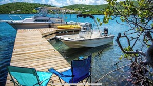 A wooden dock with two boats moored at the end, a clear blue sky, and a forested hill in the background. - Punta Aloe 20 Ocean Front Villa Apartment (Culebra)