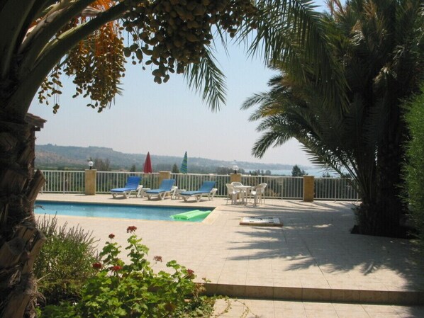A poolside area with lounge chairs, a table, and a view of the landscape.
