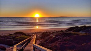 A wooden boardwalk leading to a beach with the sun setting over the ocean. - SeaChange Sceale Bay (Sceale Bay)