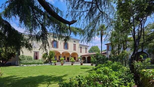 A large building with multiple arches and a well-maintained garden.