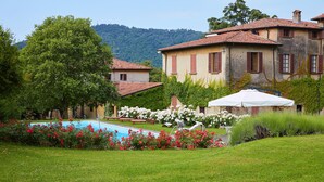 A villa with a swimming pool, surrounded by lush greenery and a mountainous backdrop.