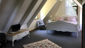 Quarto com uma cama, uma cadeira, uma escrivaninha e uma televisão.