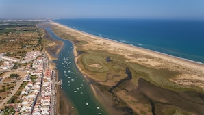 An aerial view of a coastal town with a river, beach, and residential area.
