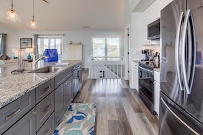 A modern kitchen with granite countertops, stainless steel appliances, and a view to the outside.