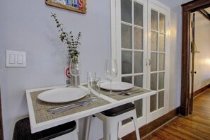 Un área de comedor con una mesa blanca para dos, un florero con planta y un cartel de 'No Fumar' en la pared.