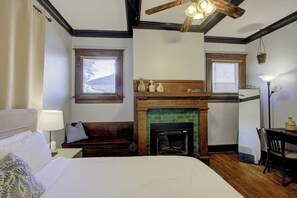 Un dormitorio con cama, un banco, chimenea y zona de comedor.