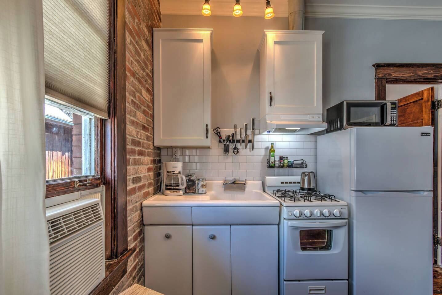 A compact kitchen with white cabinets, a stove, a microwave, and a refrigerator.