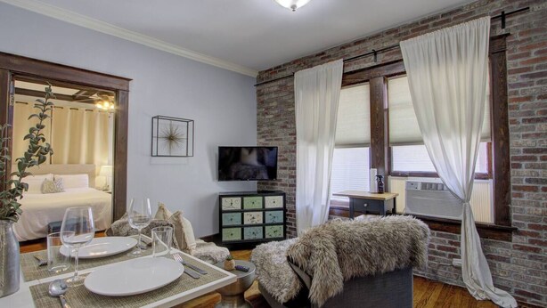 A modern living room with a dining area, a TV, and a fireplace. - Historic Midtown Getaway | Close to Beale (Memphis)