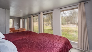 Un dormitorio con una cama grande, una silla y una ventana con cortinas.