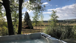 Un jacuzzi con vistas a un paisaje rural, rodeado de árboles y vegetación.