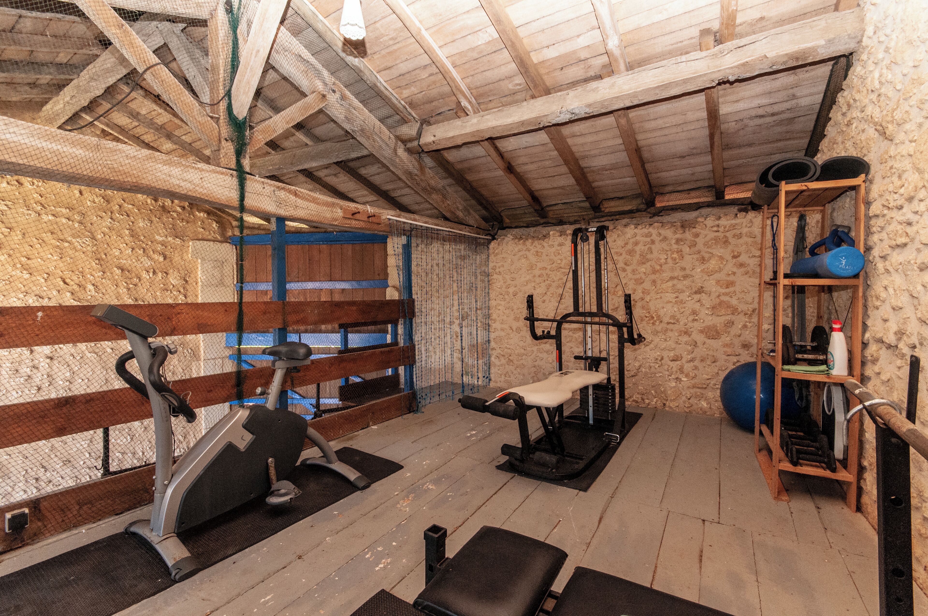 A gym with exercise equipment, a bench, and a weightlifting area.