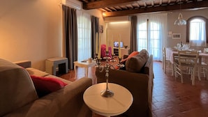 Ein gemütliches Wohnzimmer mit rundem Tisch, Sofas und einem Essbereich mit Stühlen.