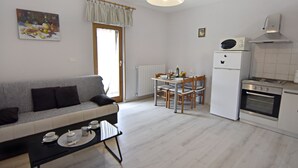 A compact living space with a sofa, dining table, chairs, a kitchenette, and a painting on the wall. - Apartment Umag-Savudrija, air conditioning, washing machine, WiFi, garden terrace (Savudrija)