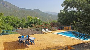 A pool area with a table and chairs, surrounded by a railing and a view of mountains. - Casa La Fresneda for 10 people (Ubrique)