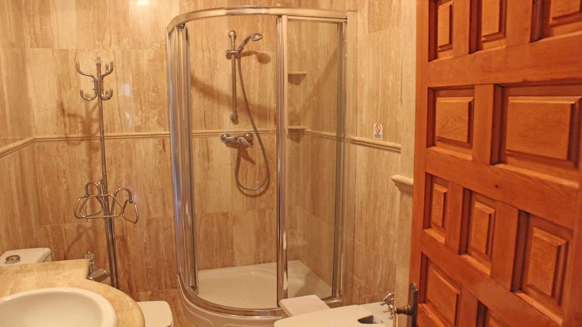A bathroom with a glass-enclosed shower, a toilet, and a sink.