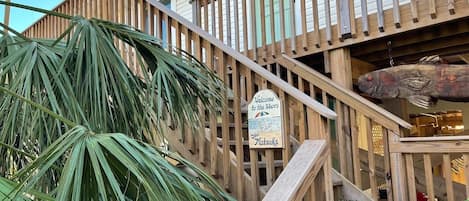 Eine Holztreppe führt zu einem Gebäude, an dem ein Schild mit der Aufschrift 'Welcome to the Shore' steht.