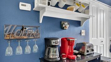 A kitchen with a blue wall, white shelves, and various kitchen appliances.
