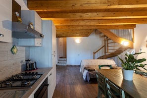Une cuisine équipée d’une cuisinière, de placards et d’un plafond en bois. Un escalier mène à une autre pièce.