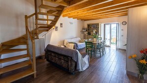Una escalera de madera conduce a un dormitorio en un altillo, con una cama, un escritorio y un comedor.
