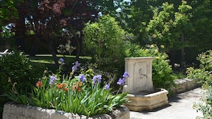 A garden with a stone planter filled with flowers and a stone bench.