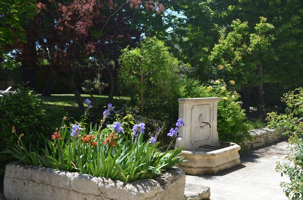 A garden with a stone planter filled with flowers and a stone bench.
