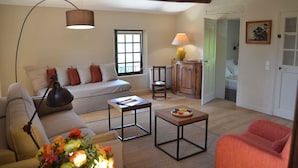 A cozy living room with a sofa, a coffee table, a lamp, and a small table with a lamp.