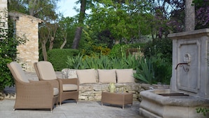 A patio area with wicker furniture, a stone wall, and a built-in barbecue grill.