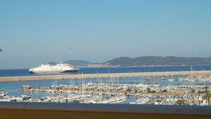 A cruise ship docked at a marina with numerous boats and a clear view of the coastline. - attic with stunning views (Alghero)