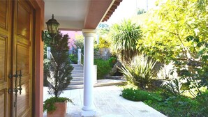 A covered entrance with a wooden door, a lantern, and a stone staircase leading to a garden area with various plants and a stone wall. - Awesome Coastal Views, Infinity Pool & BBQ area, Very Private Family Villa  (Monchique)