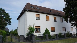 Un immeuble résidentiel de deux étages, doté d’une façade blanche, de nombreuses fenêtres et d’un toit en briques.