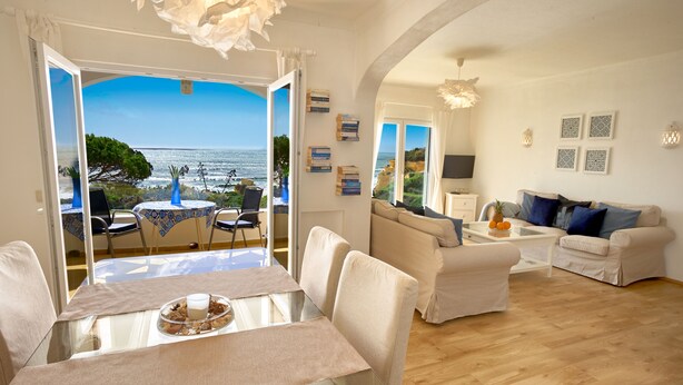 Un soggiorno con vista sul mare, una zona pranzo con tavolo e sedie, e un divano.
