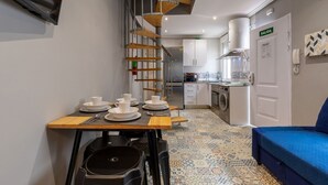 A compact kitchen with a dining area, a washing machine, and a blue sofa. - Townhouse near Plaza Castilla - Apartment CUZCO (Madrid)