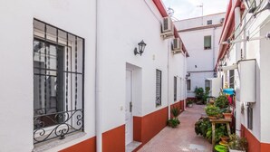 A narrow alleyway with a white building, a door, and a window with metal bars. - Townhouse near Plaza Castilla - Apartment CUZCO (Madrid)