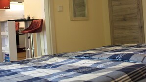 A bedroom with a bed, a wooden wardrobe, and a kitchen area visible through an open door. - Bungalow "Morgenrot", 250 m to the Müritz & jetty, alternative form of payment possible (Röbel/Müritz)