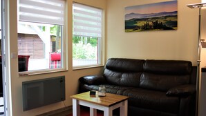 A living room with a brown leather sofa, a small wooden table with a glass jar, and a painting on the wall. - Bungalow "Morgenrot", 250 m to the Müritz & jetty, alternative form of payment possible (Röbel/Müritz)