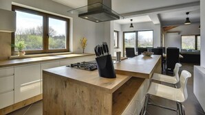 Une cuisine moderne dotée d’un îlot central, de grandes fenêtres et d’un coin repas avec des chaises.