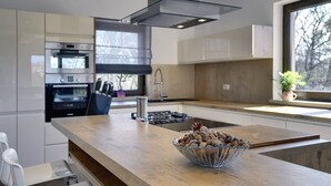 Une cuisine moderne avec un plan de travail en bois, des appareils électroménagers en acier inoxydable et un bol de noix.