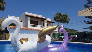 A swimming pool with two large inflatable swan floats. - 🌴 Villa Kiku Ibiza – Pool and pre-party room · 8 min Ushuaïa (Sant Josep de sa Talaia)