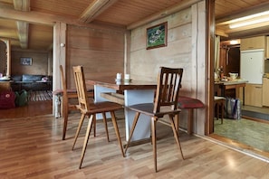 Cozy dining area with a simple table and two chairs, surrounded by warm wooden floors and walls.