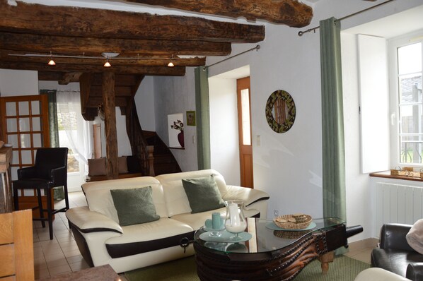Una sala de estar acogedora con un sofá blanco, una mesa de centro de cristal y una escalera de madera.