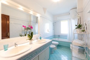 Een bad/douchecombinatie, een haardroger, badjassen, een bidet