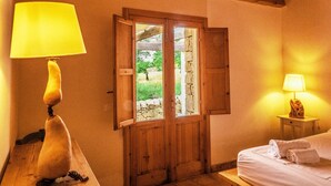 Une pièce avec une porte en bois, un lit recouvert de draps blancs et deux lampes de chevet.
