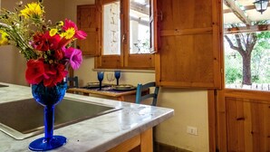Une cuisine avec des meubles en bois, un plan de travail en marbre et un vase rempli de fleurs.